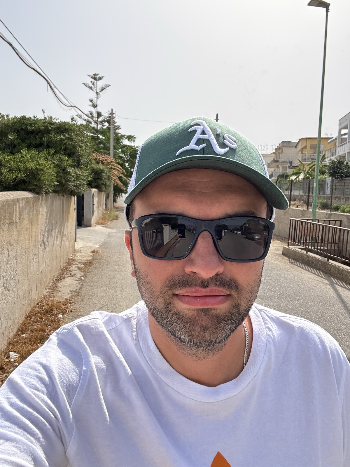 Chris Wozniczek outdoors in sunglasses and a green cap